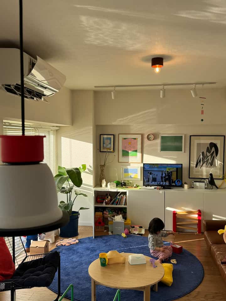 Living room with dominant blue round rug, natural wood coffee table, and kids' play area creating a bright modern atmosphere
