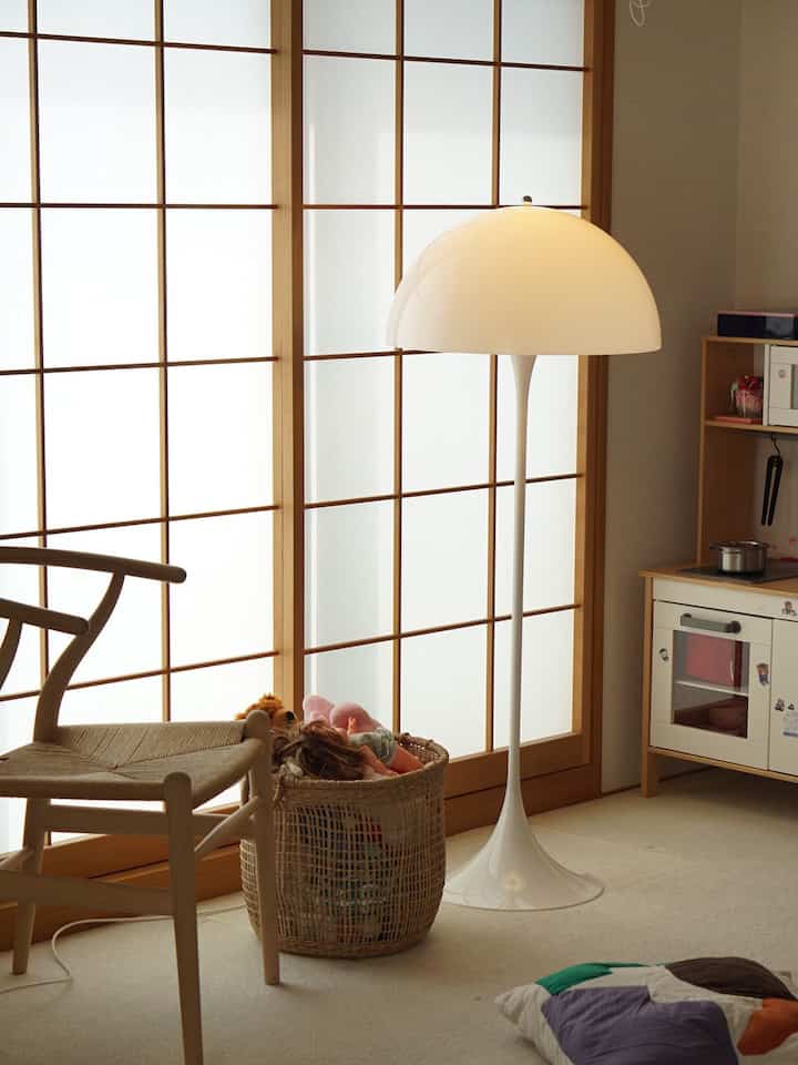 Bright Nordic kids' room with natural wood tones and furniture, featuring a Panthella floor lamp centrally placed