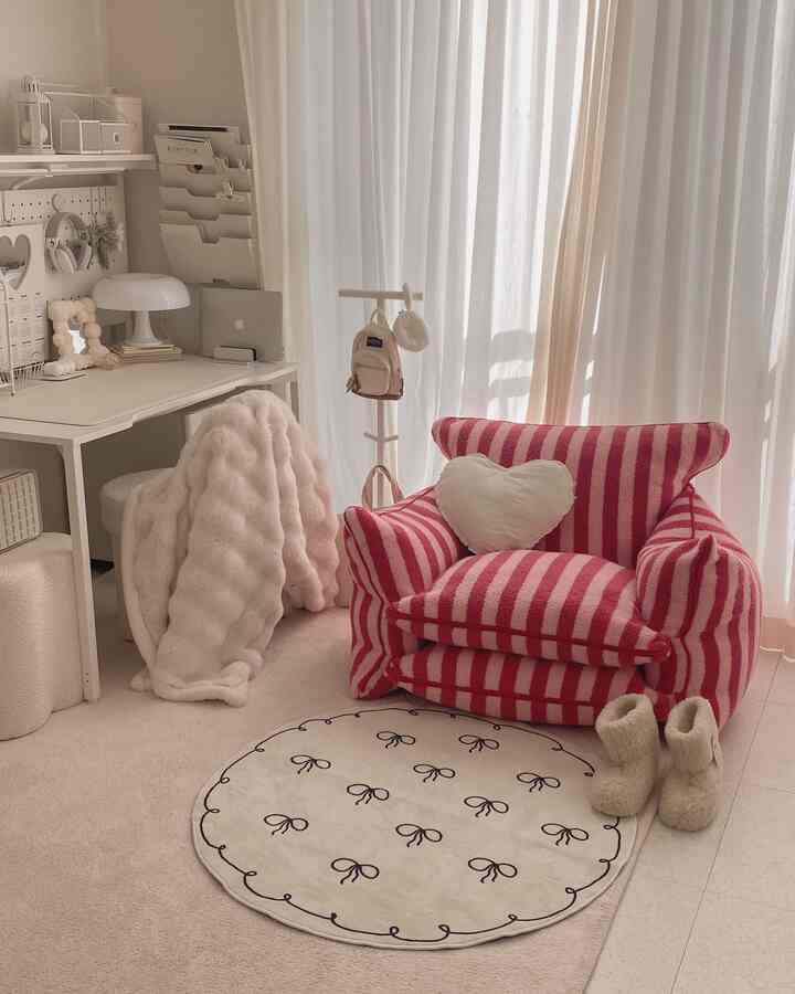 やわらかいピンクとベージュの色調の書斎、かわいいストライプのソファと丸いラグが配置された温かみのある空間