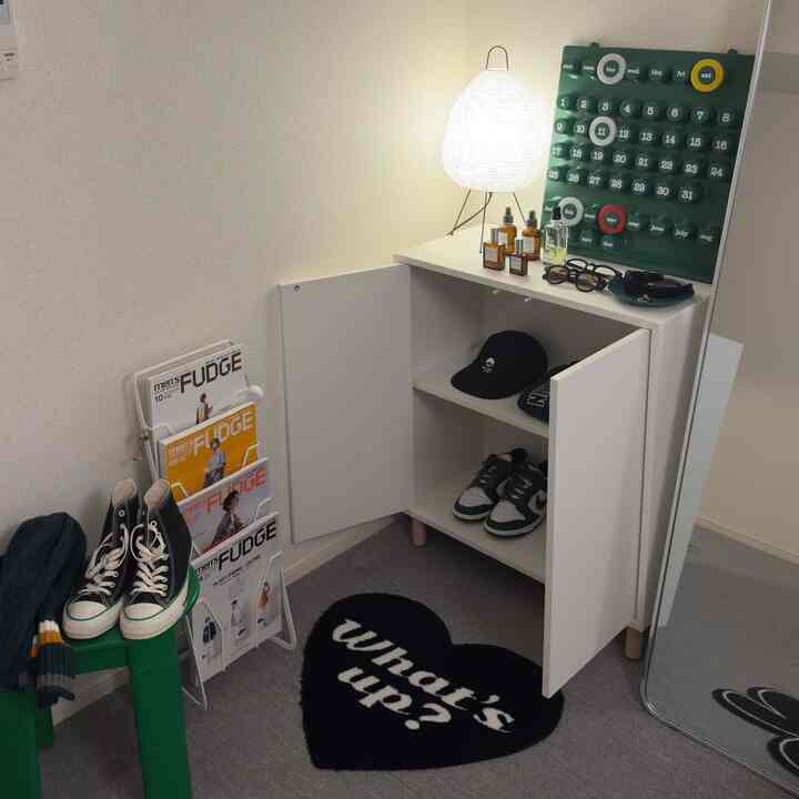 ホワイトの収納キャビネットがある玄関空間、グリーンのアクセントと大きな姿見が配置された明るく整った印象的な空間