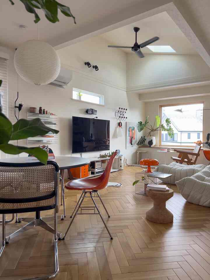 Natural wood tone and light beige walled living room featuring white sofa, orange stool, and modern furniture in cozy setting