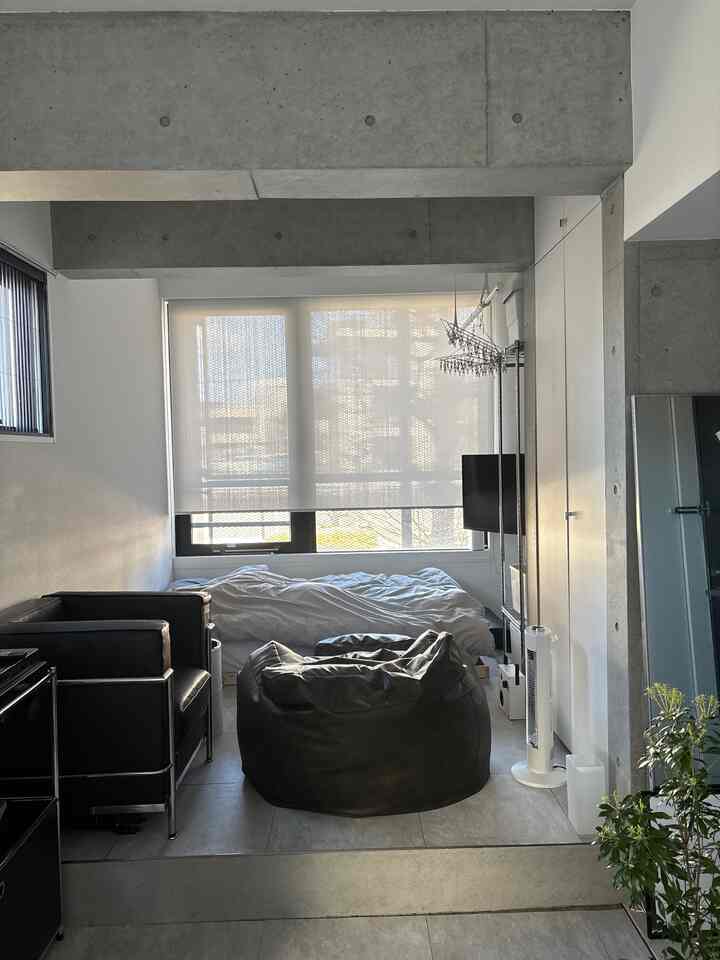 チャコールとホワイトのトーンのワンルーム寝室、黒のビーズソファとベッドが配置されたモダンなインテリア