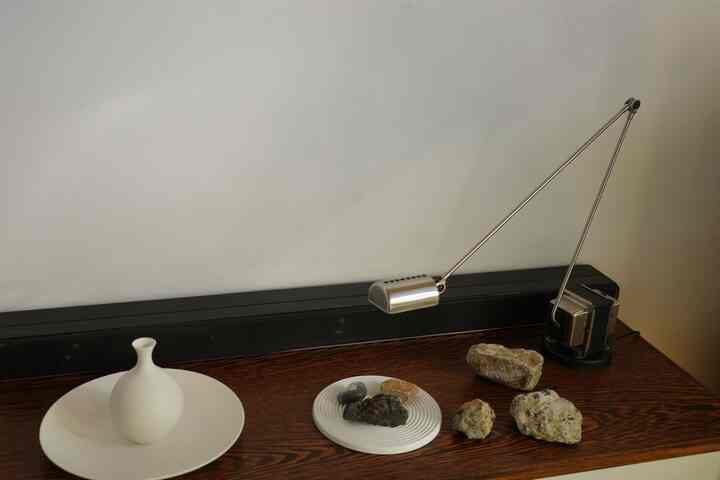 Brown wood-toned sideboard with white ceramic vase and industrial-style lamp, natural and minimalist ambiance
