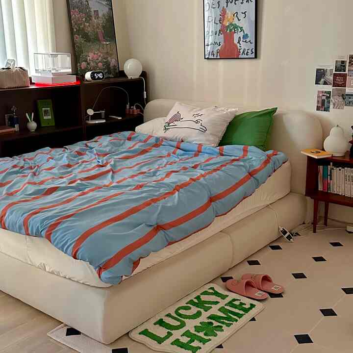 白と緑の調和が取れた寝室、ベッドとラグ、ナイトテーブル、本棚が配置された雰囲気のあるインテリア