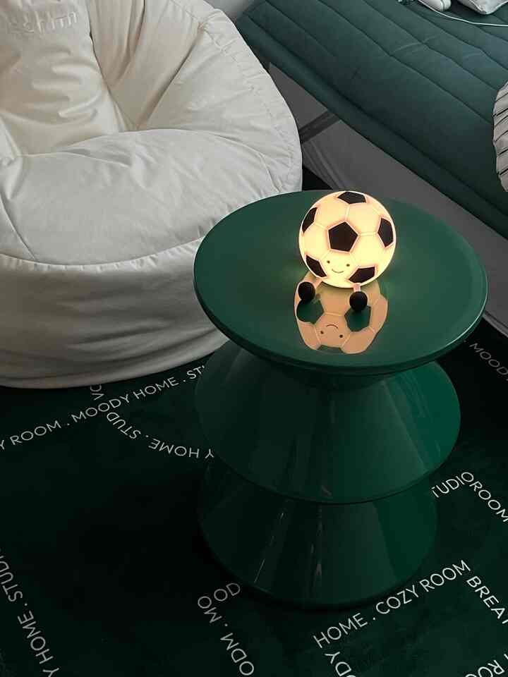 ブルーとグリーンのトーンのリビング、白いビーズクッションとグリーンのミニテーブルにサッカーボールのランプが置かれた雰囲気のある空間