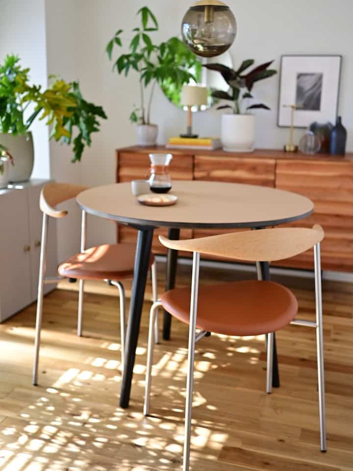 Natural beige and brown toned dining room featuring a round dining table and leather dining chairs in a cozy setting