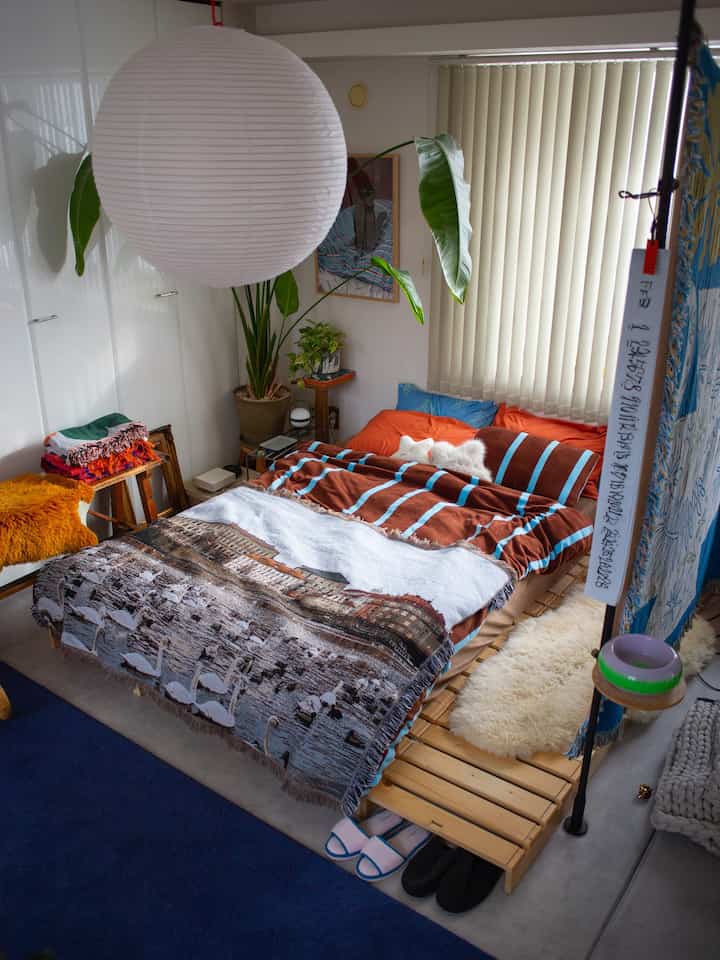 白い照明とブラウン色のベッド、植物が配置された自然な雰囲気の落ち着いた寝室空間