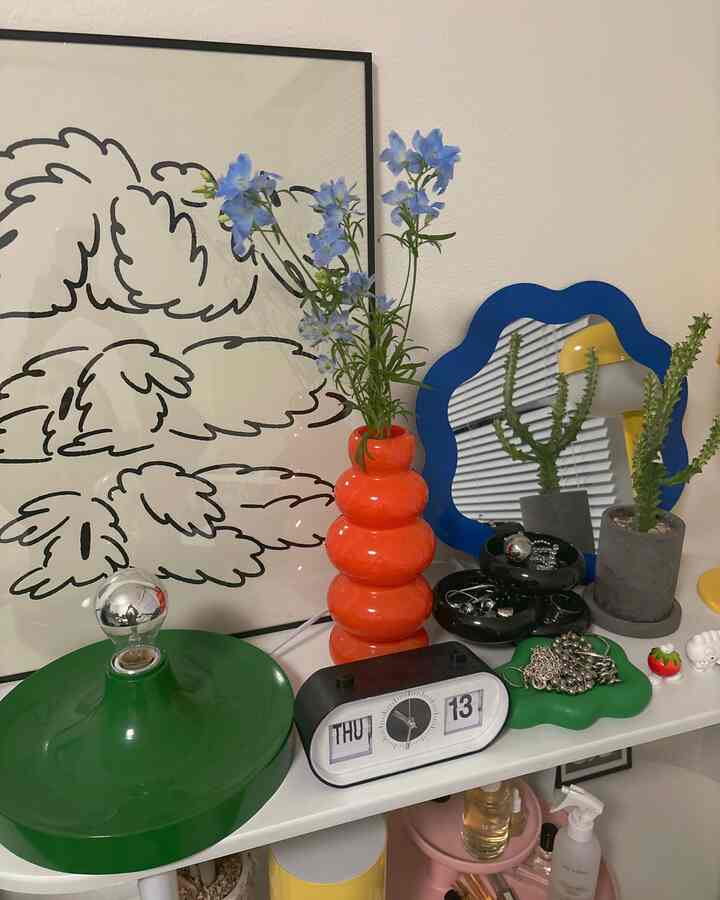 オレンジの花瓶と青い花が置かれた韓国風のインテリア棚のある印象的な空間