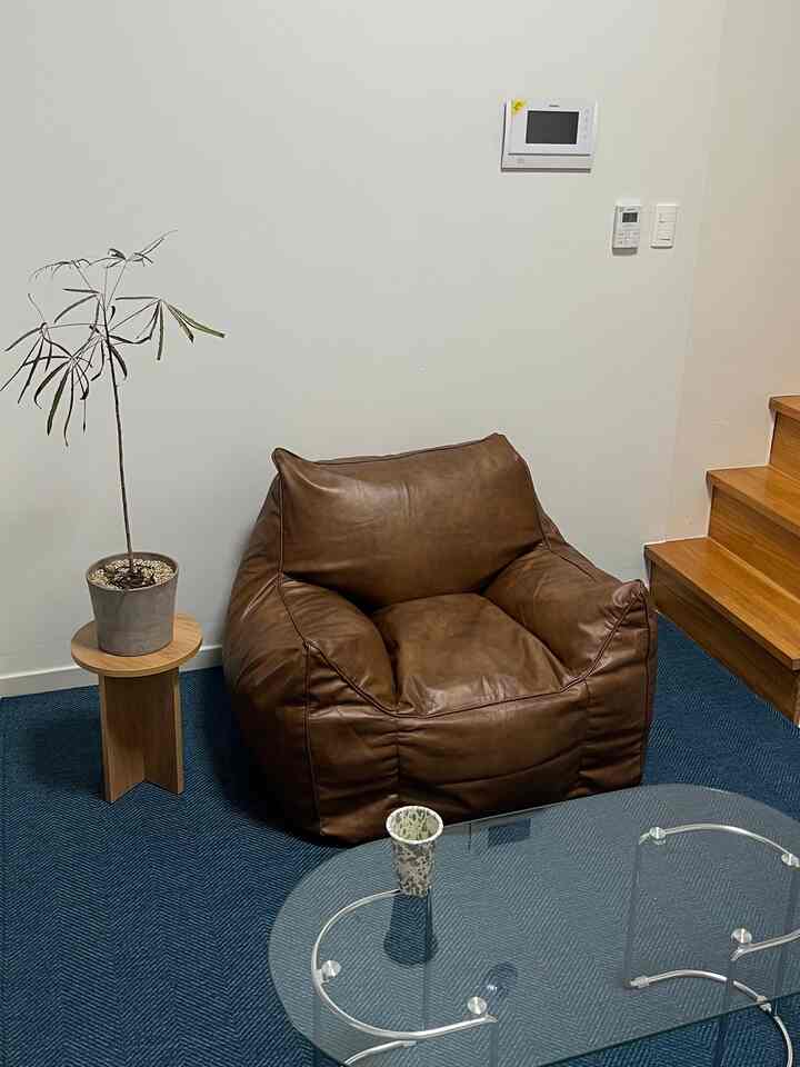 Navy-toned rug with brown bean bag and wooden side table in a tidy living room space