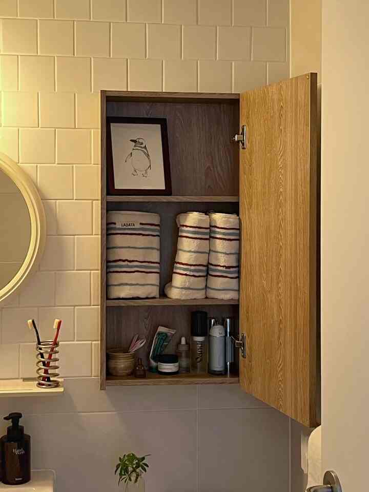 木目調と白の浴室キャビネット、整然としたタオルと洗面用品が配置された清潔感のある空間