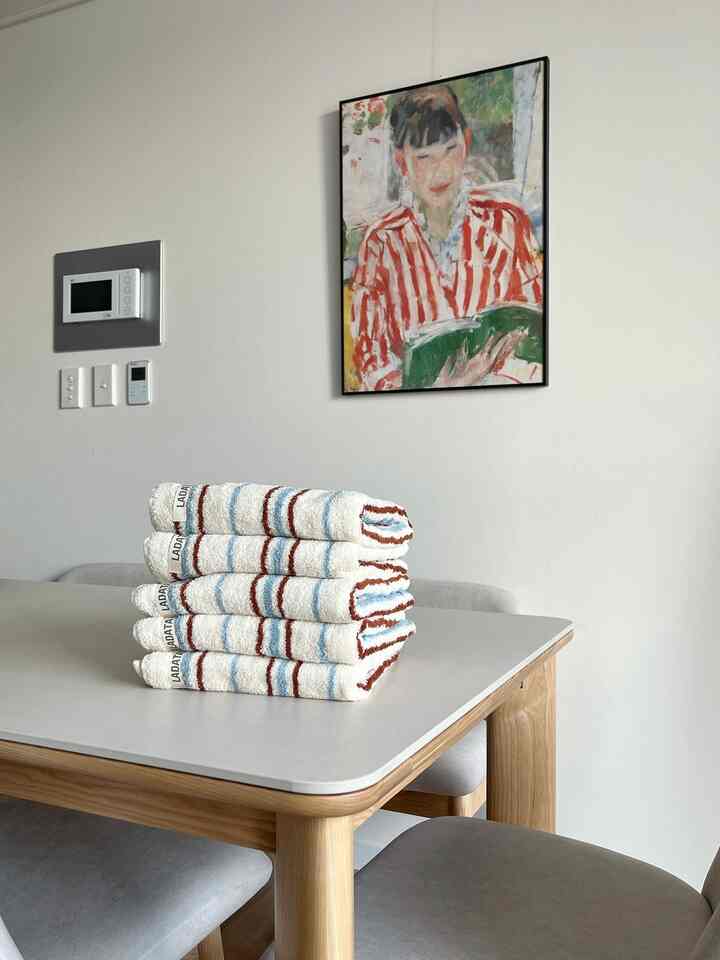 白い壁とナチュラルな木製ダイニングテーブルとグレーの椅子が置かれた4人用のダイニングルーム、上部に人物のポスターが飾られている空間