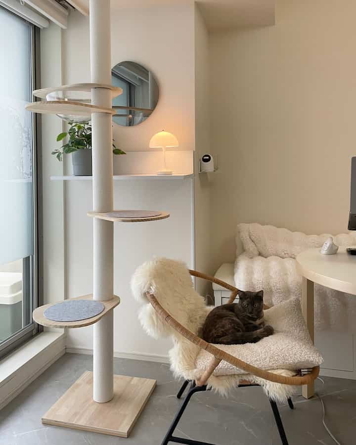 白と木目調が調和したナチュラルなリビング、キャットタワーと居心地の良い椅子でくつろぐ猫がいる雰囲気のあるインテリア