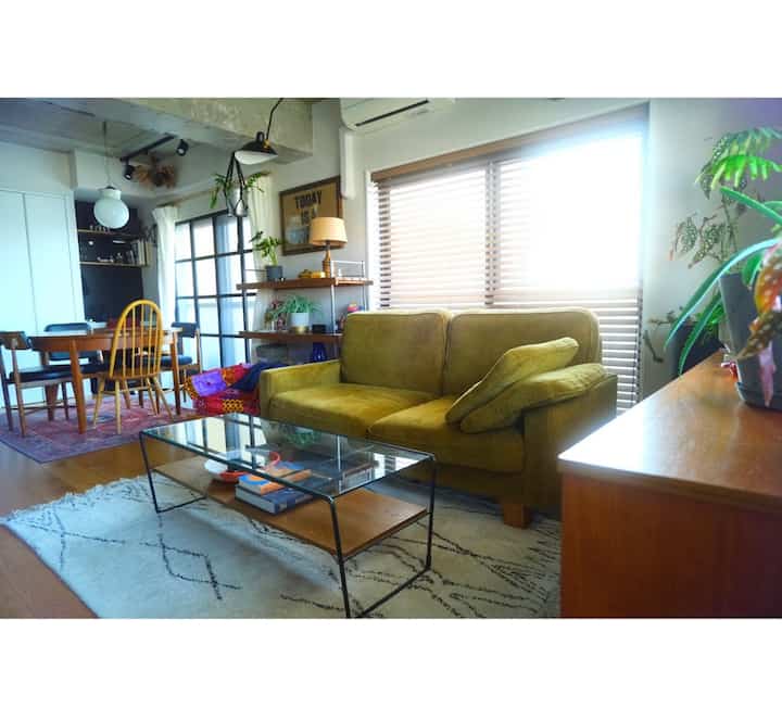 Natural wood-toned living and dining room featuring a yellow sofa and glass coffee table with cozy atmosphere