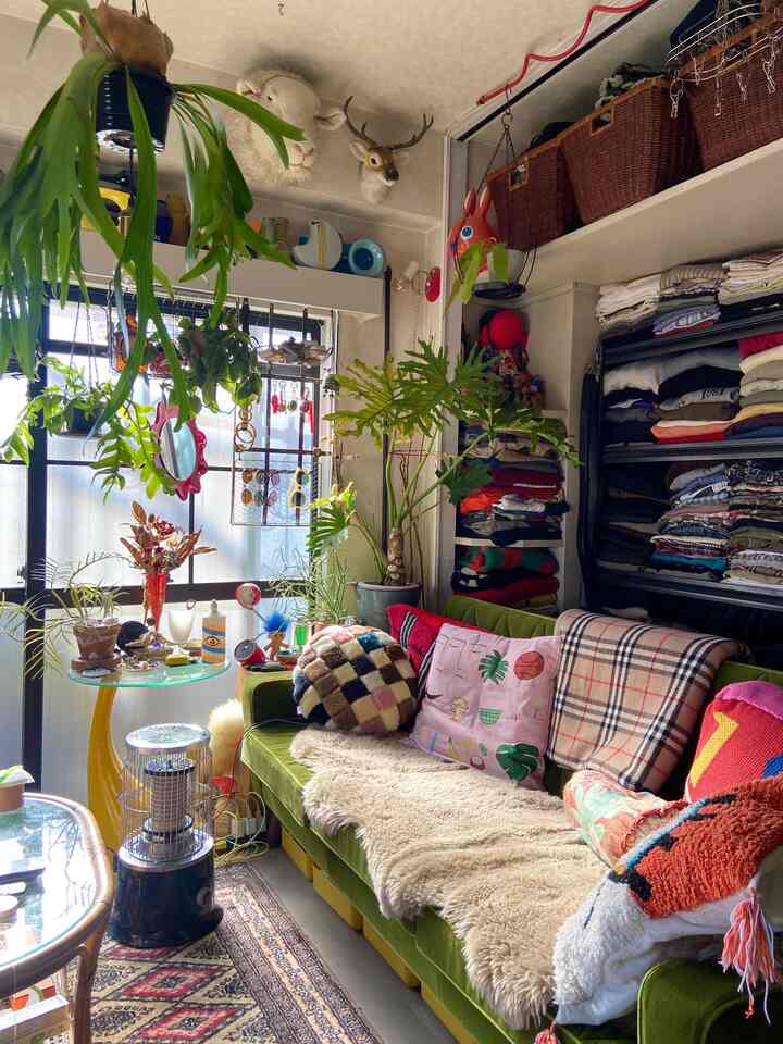 Natural-tone living room featuring a green sofa with various cushions and a mouton cover creating cozy atmosphere