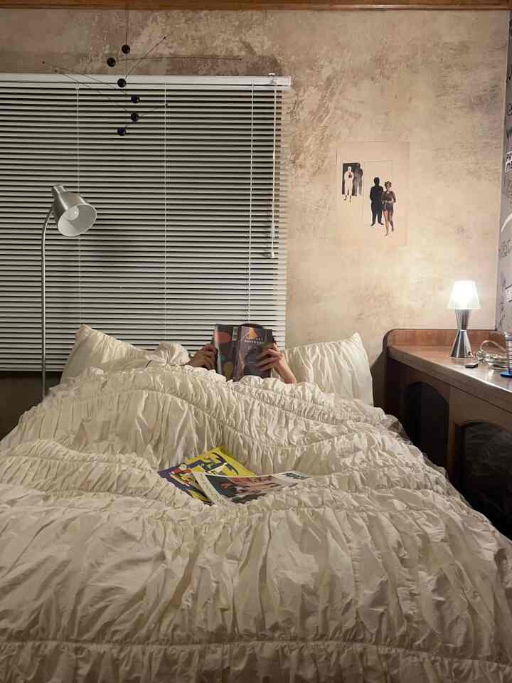 Beige-toned wall bedroom featuring white bedding, mid-century modern mobile and floor lamp creating cozy atmosphere