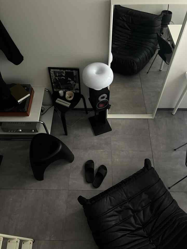 黒いレザーソファと大きな姿見があるモダンな玄関スペース