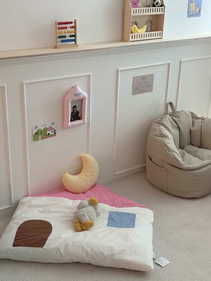 White and pink toned kids' room featuring a rug and bean bag chair creating a cozy space