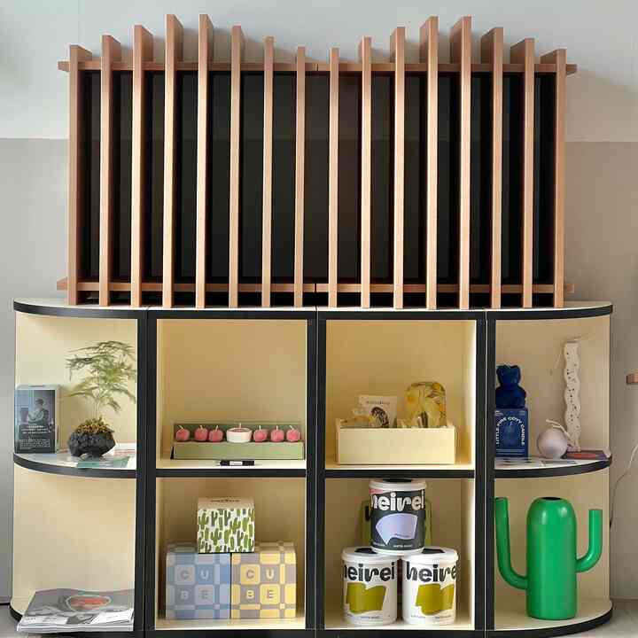 ナチュラルなベージュの壁とダークブラウンの木製スラットが配置され、多様なオブジェが飾られた収納棚のある実用的な空間