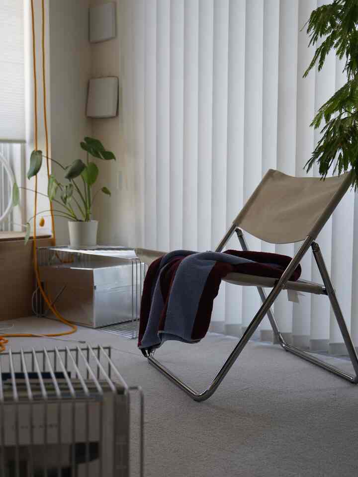 Bright natural light room featuring a beige canvas modern armchair with chrome frame and a potted plant
