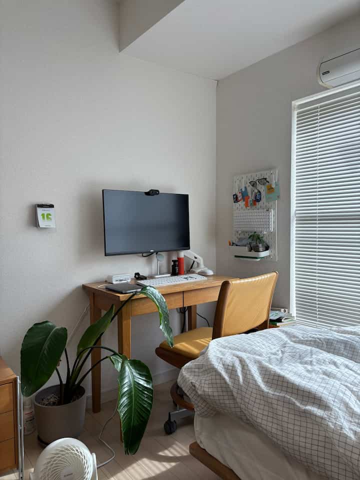 Natural wood-toned 7-tatami 1K studio featuring a white wall and a compact home office desk setup