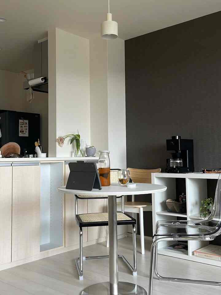 白と茶色の落ち着いた色調のダイニング、ミッドセンチュリーモダンの椅子とペンダントライトが配置されたコンパクトなホームカフェ空間