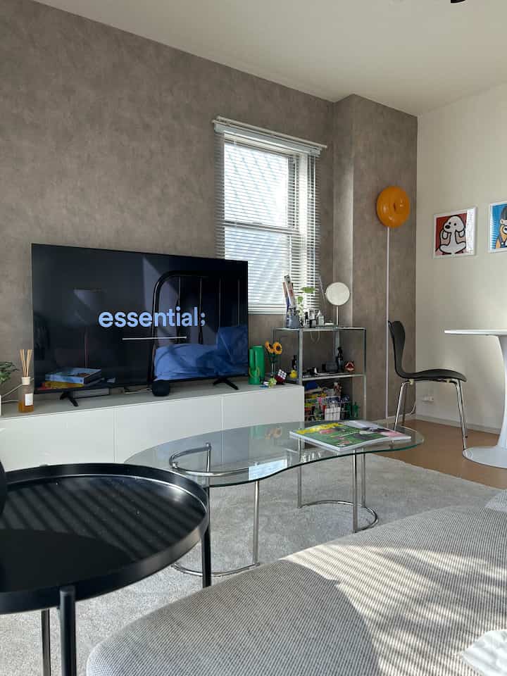 Modern 1LDK living room in white and gray tones featuring sofa, glass coffee table, and TV stand with bright natural lighting