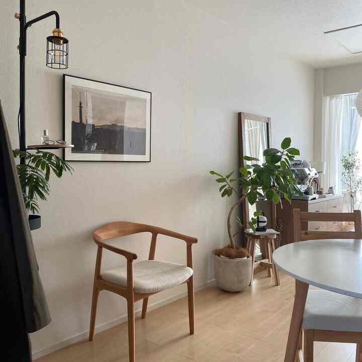 White-walled, wood-toned Nordic-style long living room featuring dining table, indirect lighting, and leafy plants in harmony