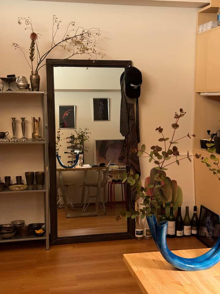 ナチュラルな木目調の1LDK一人暮らし向けリビングダイニング、 大きな鏡と植物の飾りが配置された雰囲気のあるインテリア