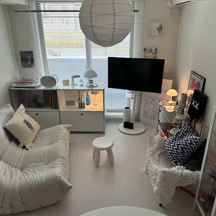 A white and natural toned living room featuring a central stool and modern sofa with a simple, modern interior design
