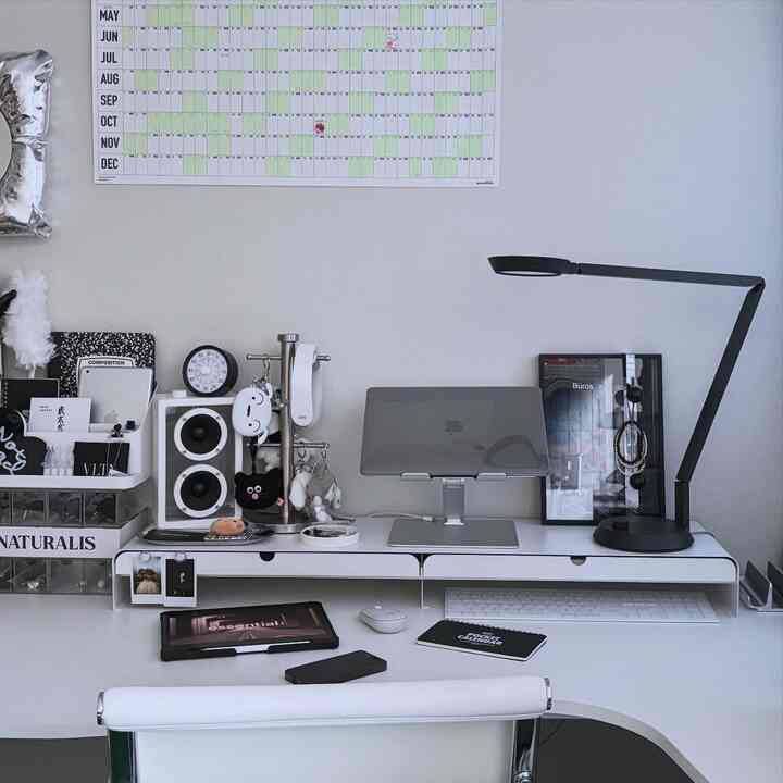 白と黒のモノトーンのホームオフィス、清潔なデスクとモニタースタンド、LEDデスクランプが配置されたシンプルモダンな空間