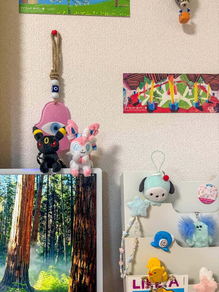 White-walled space with desk featuring pink and colorful plush toys placed on and around the desk, creating a cozy workspace