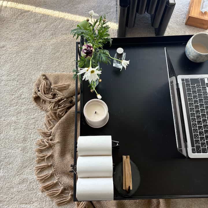 ベージュの毛布と黒のローテーブルがあるリビング、花とキャンドルが配置された落ち着いた雰囲気のインテリア