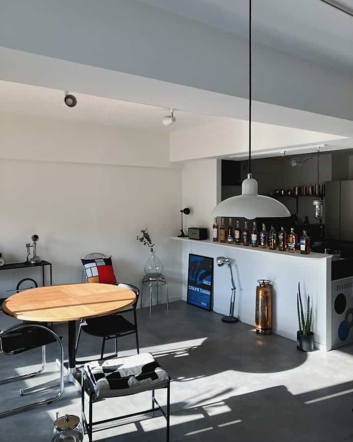 White and black wood-toned dining room featuring industrial style home bar and minimalist atelier space
