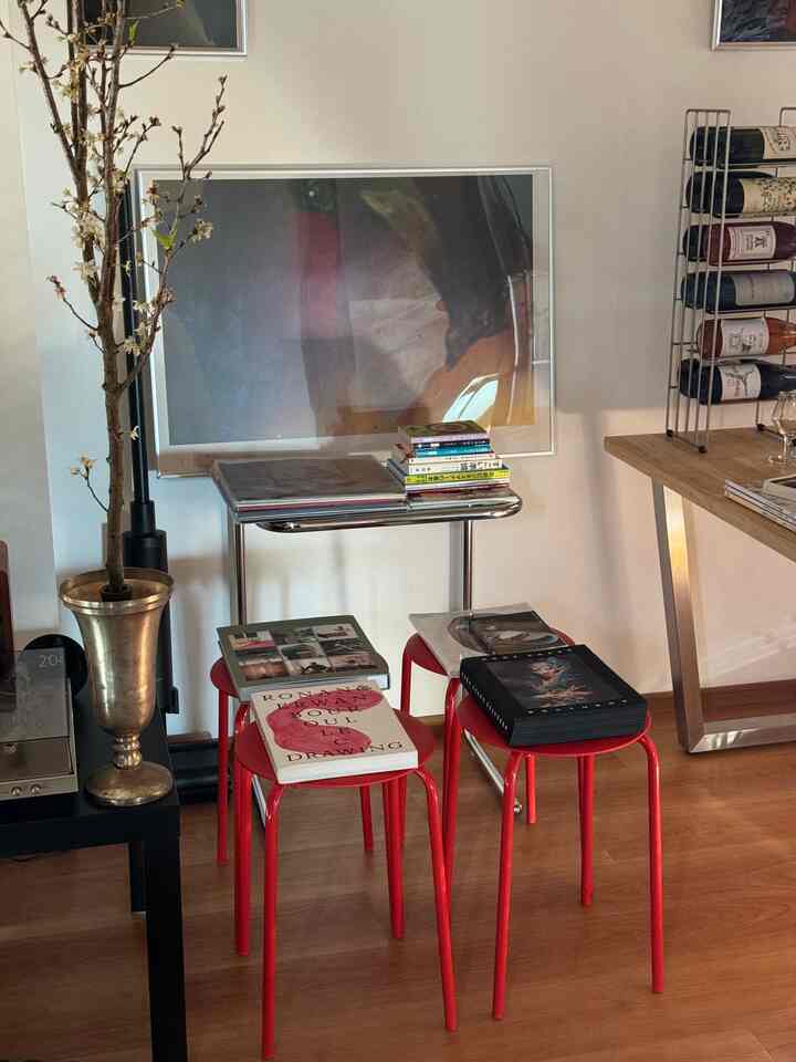 赤いスツールが中央に配置された1LDKの空間、木目調の床とワインラックが温かみのある雰囲気を作るおうちカフェコーナー