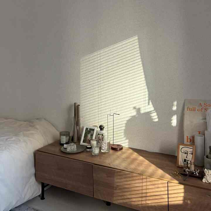 優しいホワイトとブラウンの色調の寝室、木製キャビネットに置かれたキャンドルが落ち着いた印象的な空間を演出