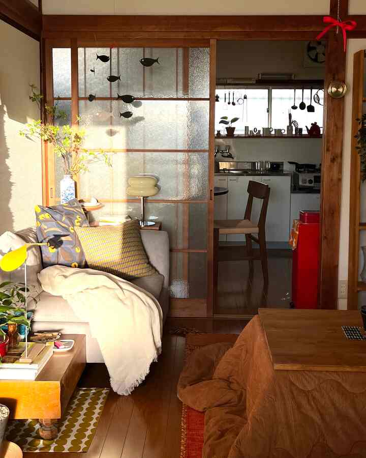 Beige sofa and brown wooden furniture harmonize in a single household living room, connected to a kitchen through Japanese sliding doors, creating a cozy interior