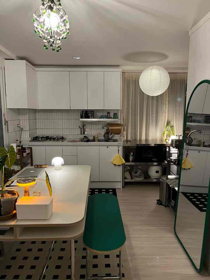明るいホワイトとグリーンのキッチンスペース、ミッドセンチュリーモダンのダイニングテーブルとベンチが配置された雰囲気のあるカフェ風インテリア