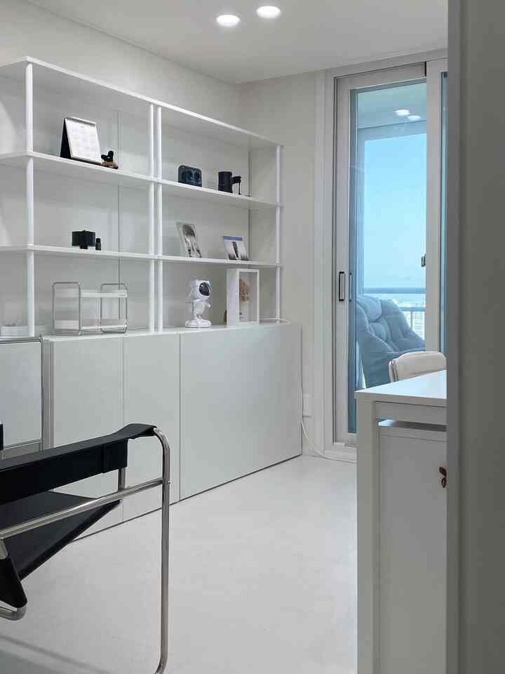 明るく清潔感のある白を基調としたワークスペース、白いキャビネットとデスク、革とスチールの椅子が配置されたモダンな空間