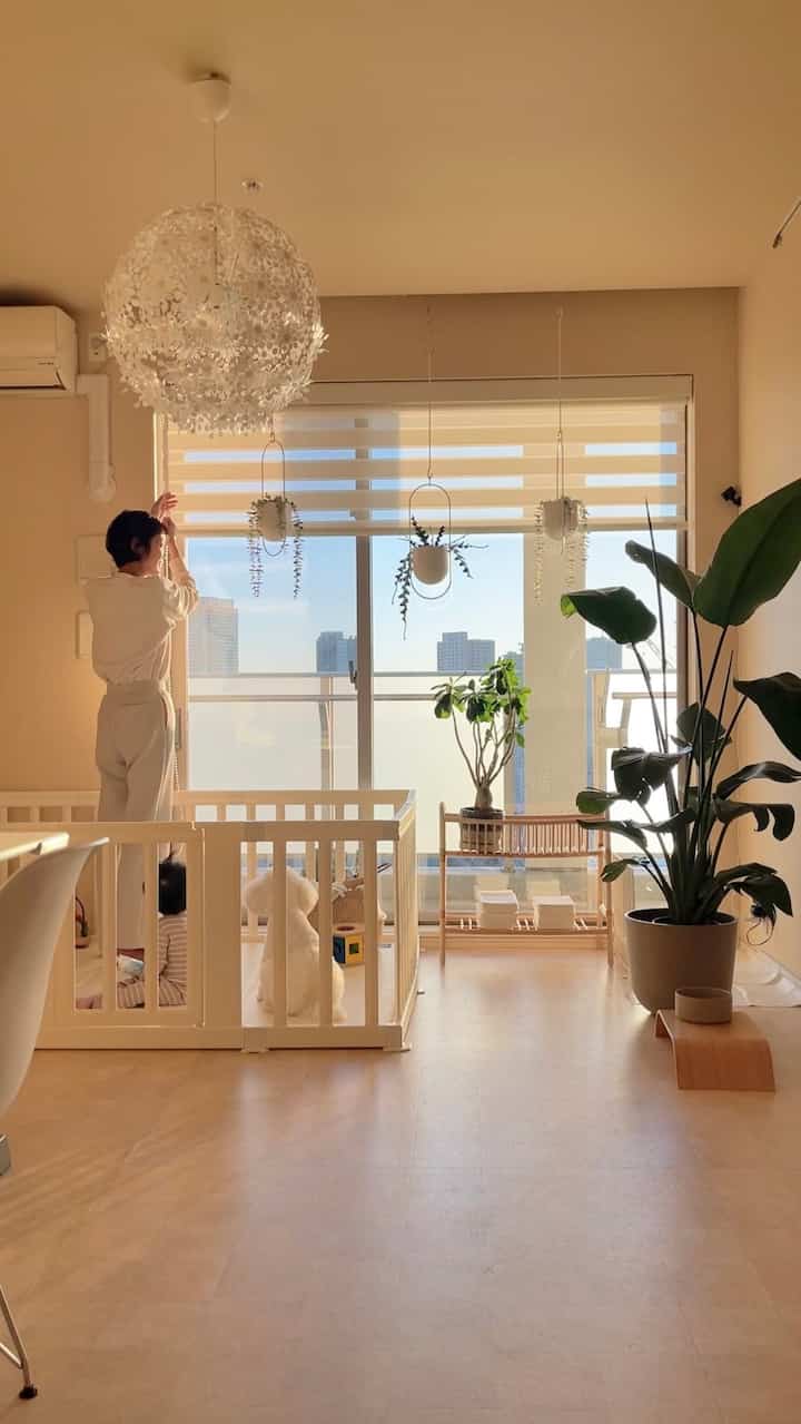 暖かいベージュの色調のリビング、赤ちゃんと犬の遊び場があり、植物が調和した自然な雰囲気のあるインテリア