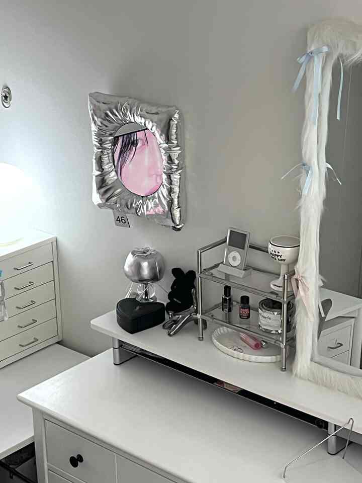 ホワイトとシルバーのトーンが印象的なモダンな化粧台空間、チェストと個性的な鏡が配置されたインテリア