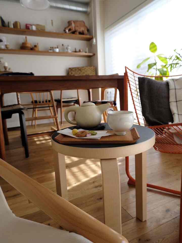 ナチュラルな木目調と白い壁のリビング・ダイニングルーム、スツールに茶器が置かれた雰囲気のあるカフェ風インテリア