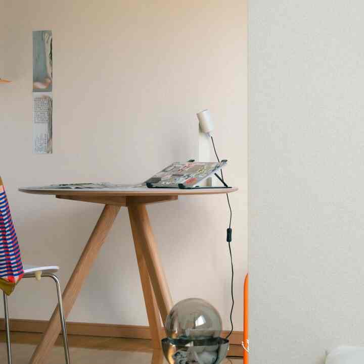 ナチュラルカラーのリビング、丸い木製のダイニングテーブルと椅子が配置された居心地の良い一人暮らし空間