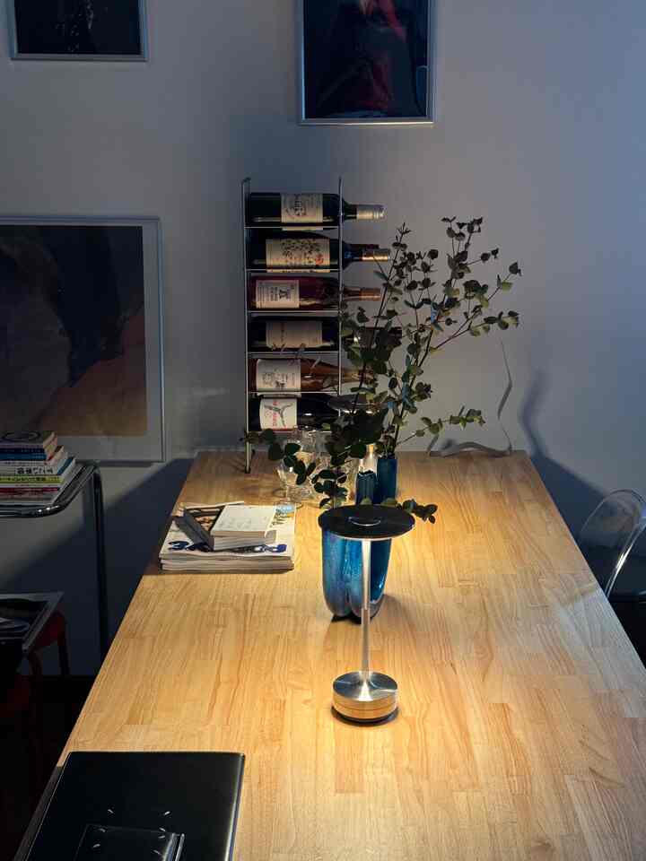 ナチュラルな木目調の1LDKダイニング、ワインラックとモダンなテーブルランプが配置された印象的な空間