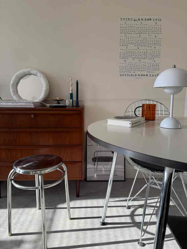 白と茶色の色調が調和するダイニング、丸いダイニングテーブルとミッドセンチュリーモダン家具が配置された雰囲気のある空間