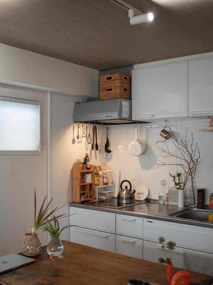 White and natural tone studio apartment kitchen featuring tidy storage and kitchen utensils in a compact cooking area