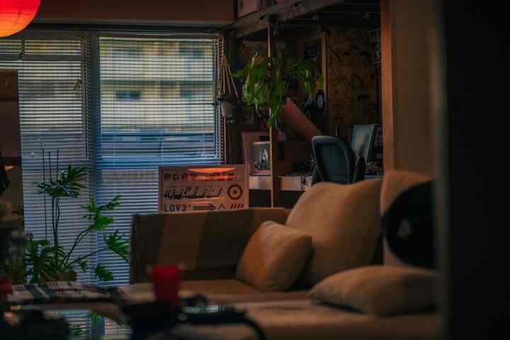 ナチュラルカラーと木目調が調和したリビング、ベージュのソファと植物、ホームオフィスのデスクが配置された落ち着いた雰囲気のインテリア