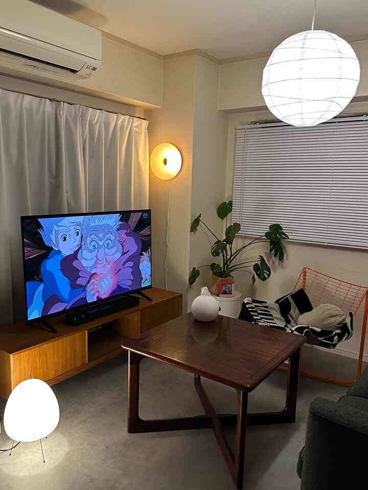 ナチュラルカラーの1LDKリビング、木製のテーブルとテレビ台、照明が印象的な落ち着いた空間