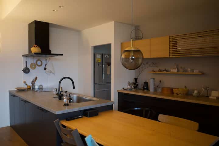 Simple kitchen and dining room featuring black cabinets and wood tones with pendant lighting as a focal point