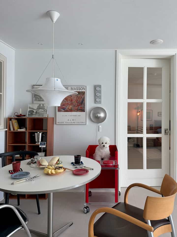 白と赤の色調のダイニングルーム、犬用の赤いペットチェアと丸いダイニングテーブルが配置された雰囲気のあるインテリア
