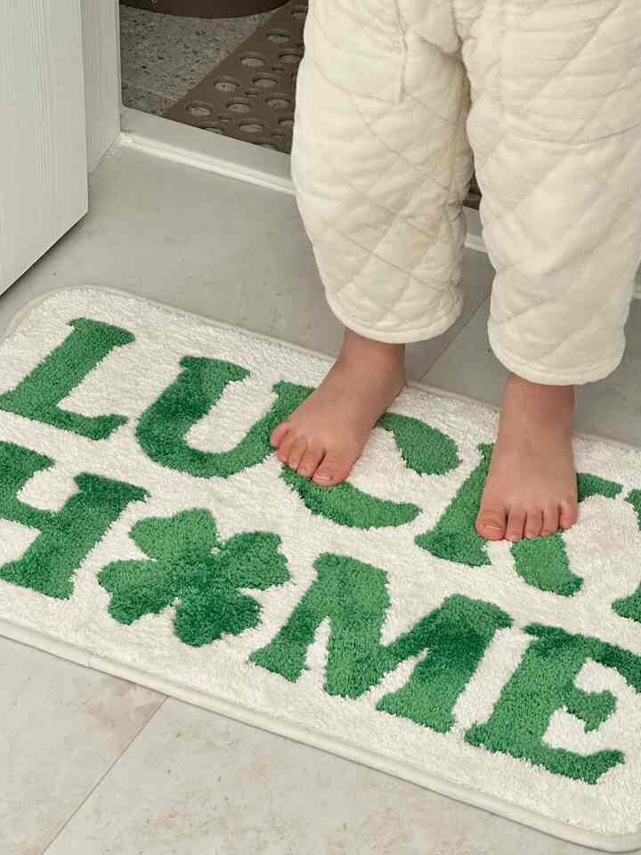 Entrance area with white floor and door featuring a green patterned bath mat with child feet on top, creating a cozy atmosphere